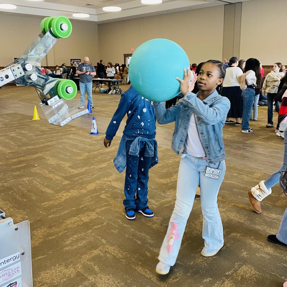 A girl holding a big blue ball.